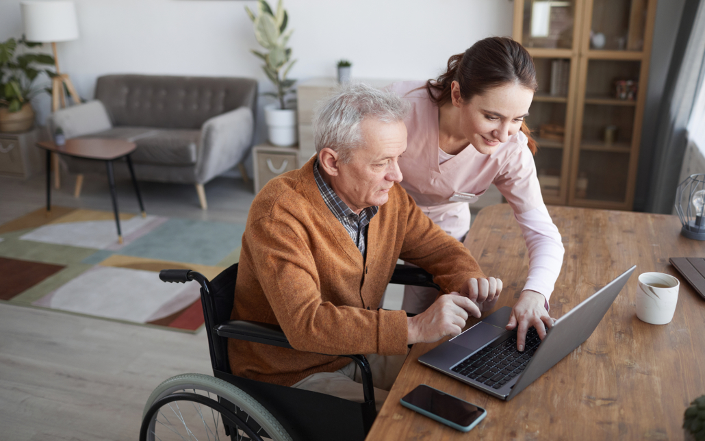 Female caregiver helping older man with computer