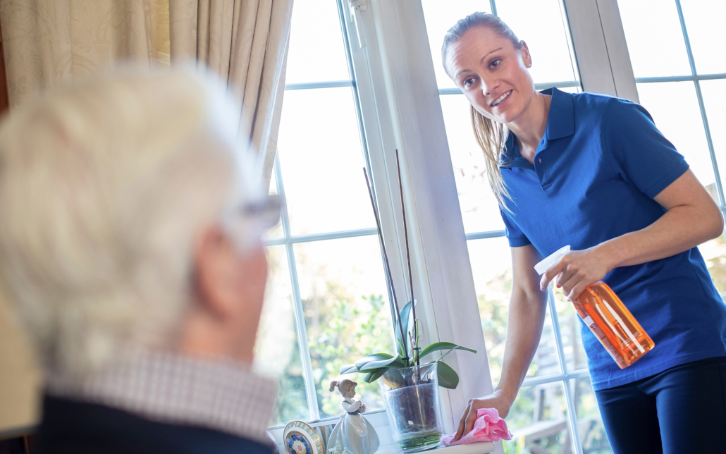 Woman with cleaning spray speaking with older man