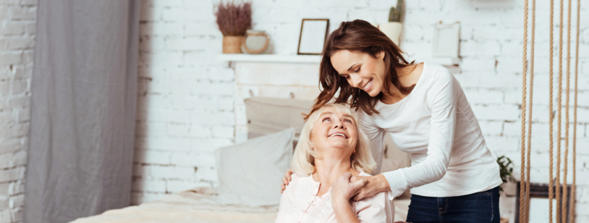 Female caregiver helps older woman into her wheelchair