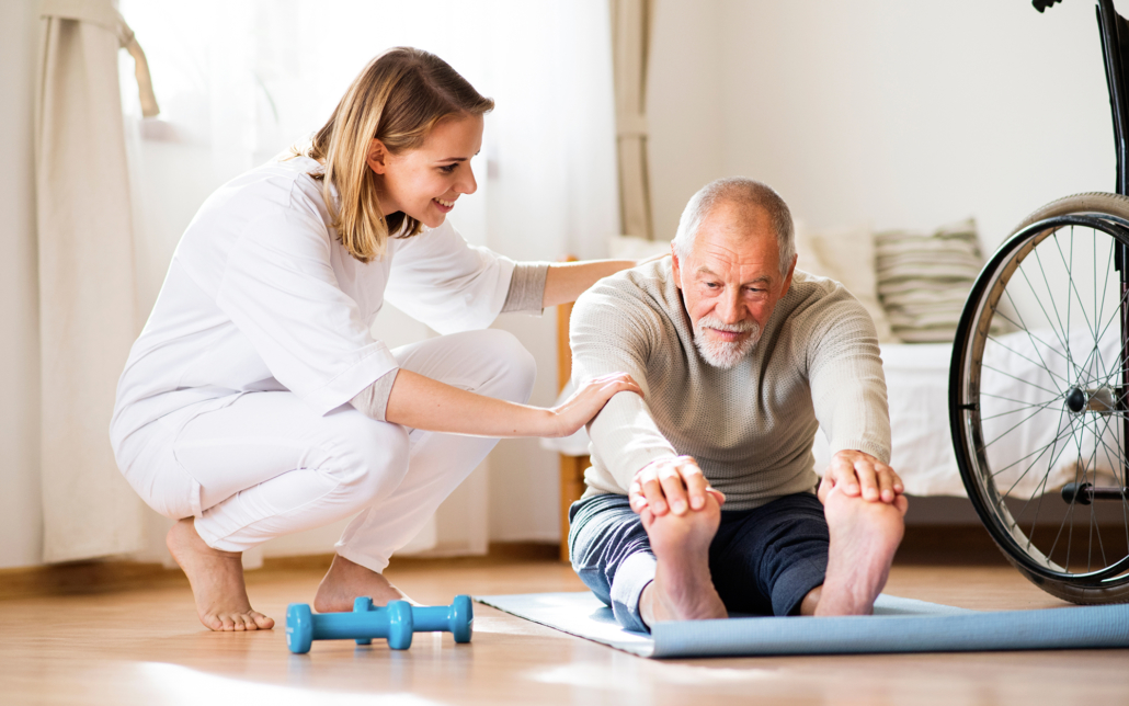 Older man stretches with the help of female caregiver