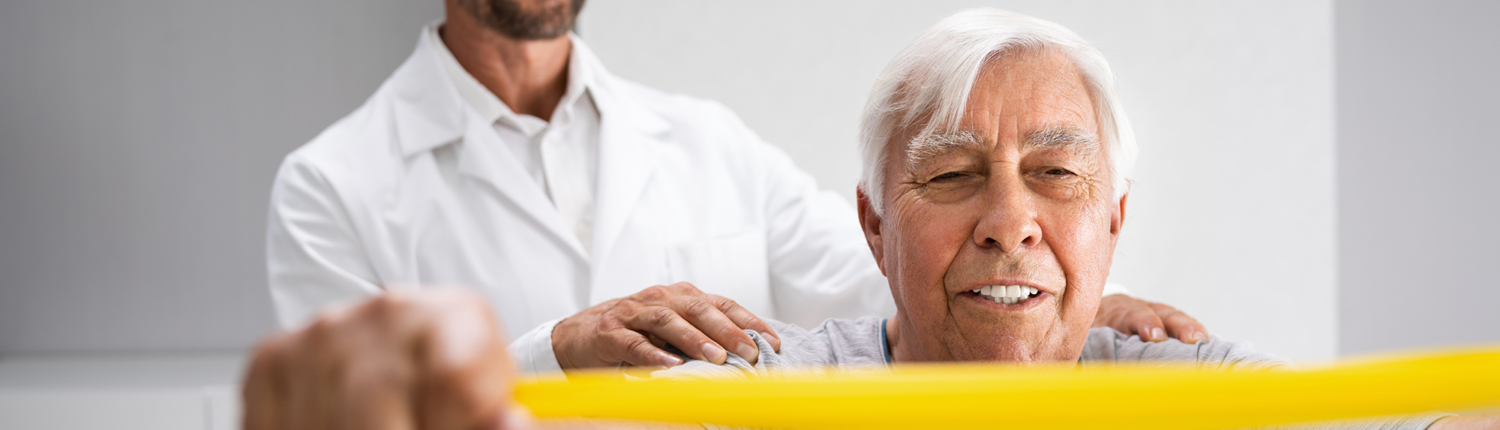 Older adult performing physical therapy with the help of a male physician