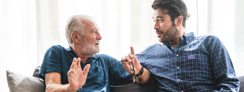 Older man discussing adult day care with a younger man on the couch