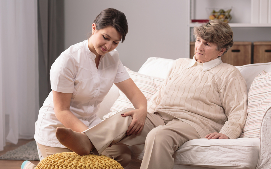 Female caregiver helping older woman level her leg