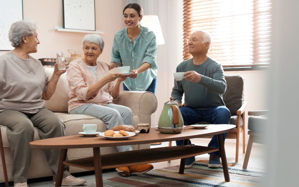 Female caregiver handing a group of older adults cups of tea