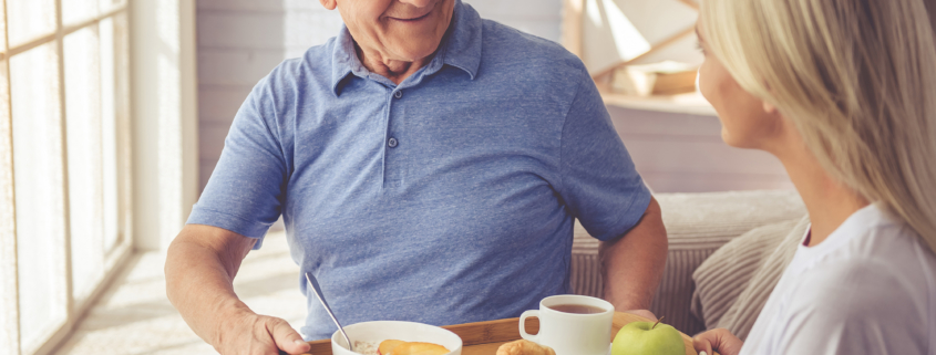 Young woman passing tray of food to older man