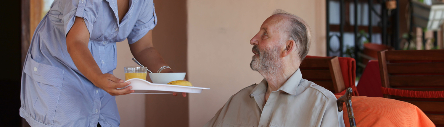 Female caregiver serving breakfast to a disabled man